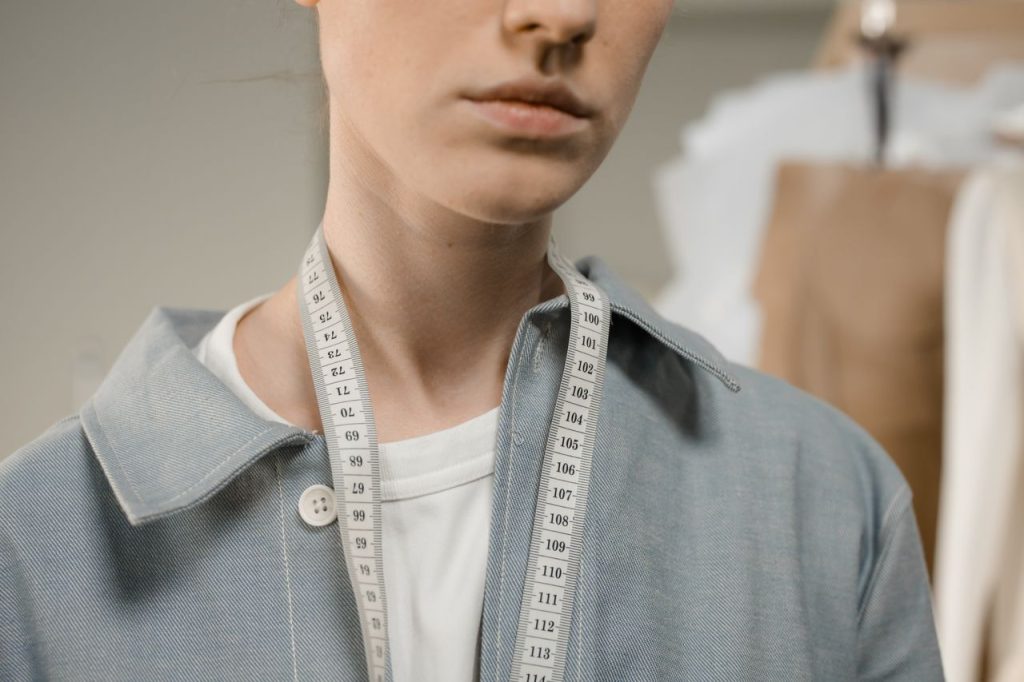 Mastering the First Impression: Your intriguing post title goes here A fashion designer in a studio with a measuring tape draped around the neck, showcasing precision and creativity.